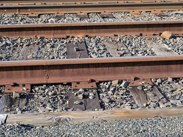 A rusted rail stamped 1955 Lackawanna, on timber ties and ballast.