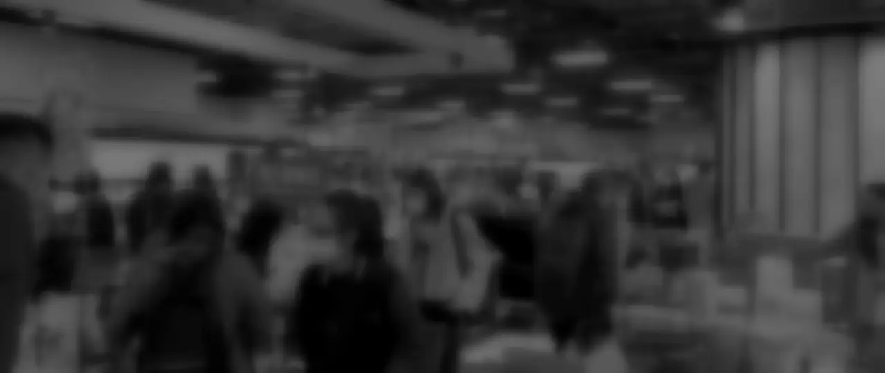 A busy supermarket floor, blurred and grey, shoppers between produce stands and fridges.